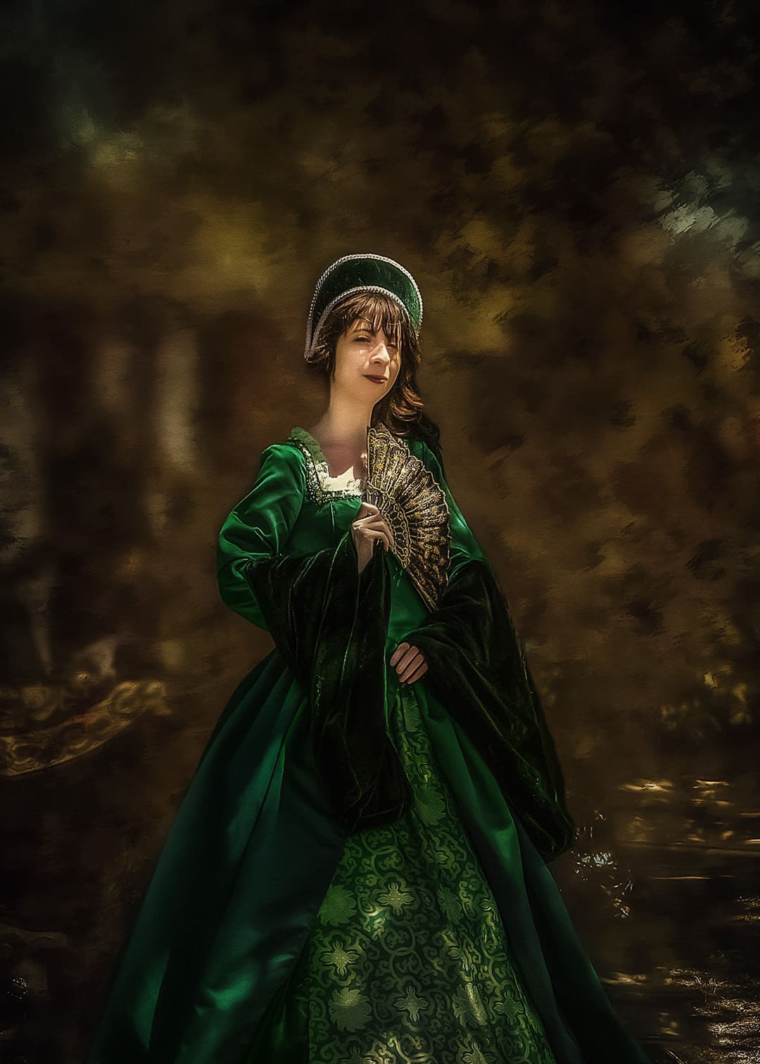 Portrait of a woman in an emerald green Renaissance-style gown holding a gold fan at the West Texas Renaissance Festival in Odessa, Texas.