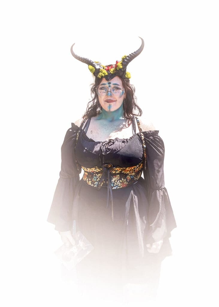 Woman in a fantasy-inspired costume with horns, floral details, and blue face paint at the West Texas Renaissance Festival in Odessa, Texas.